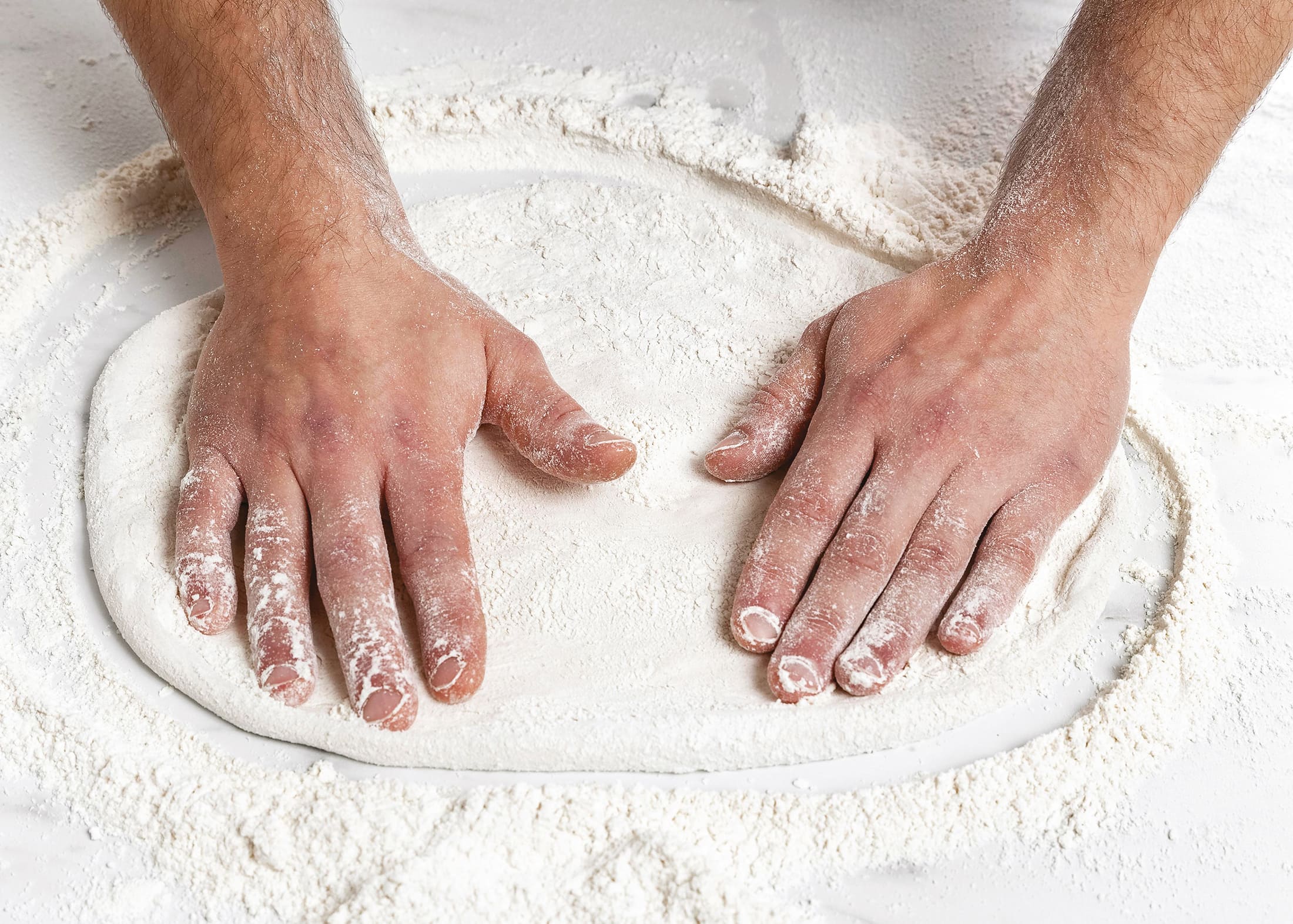mani che impastano la pizza con impasto artigianale